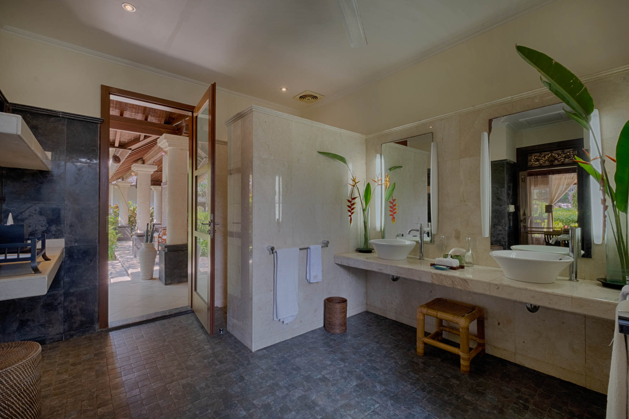 Spacious villa bathroom with twin vessel sinks, marble counter and garden-view doorway at Sanga Sanga, Bali