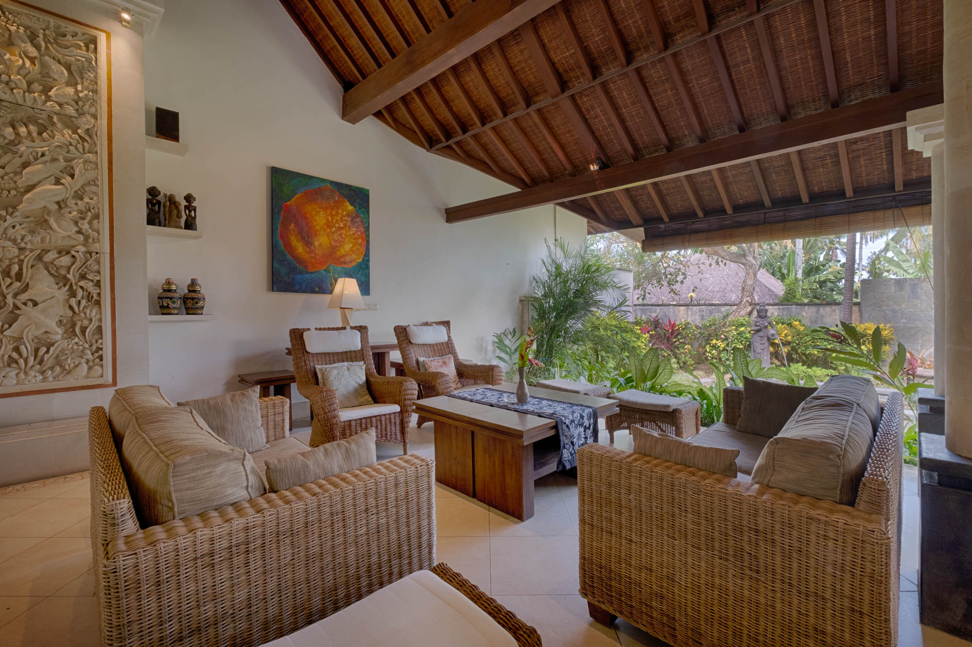 Open-air villa living lounge with rattan sofas, vaulted timber ceiling and tropical garden view at Sanga Sanga, Bali