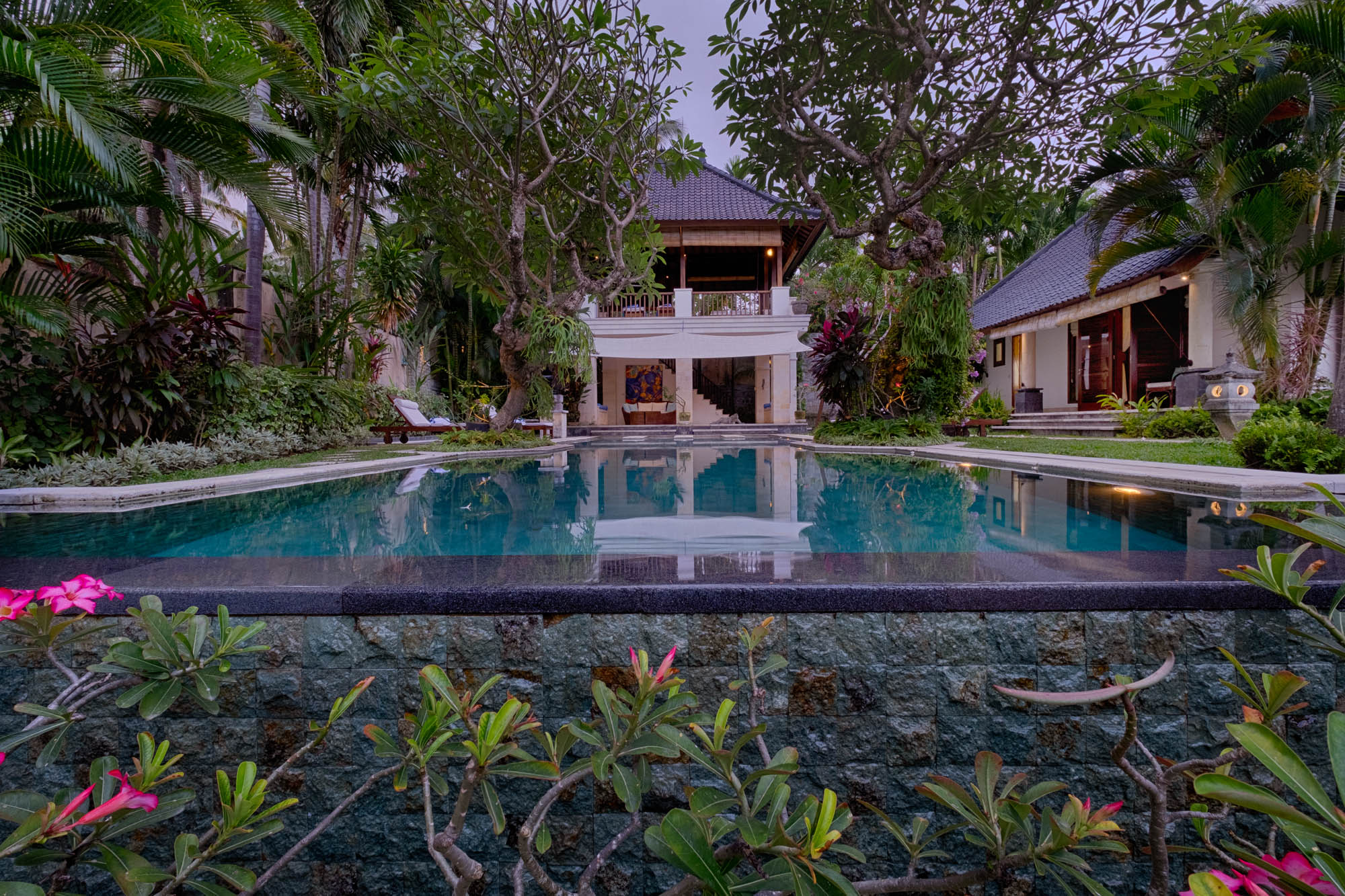Private villa swimming pool framed by frangipani and palms at dusk, Sanga Sanga Hospitality, Bali